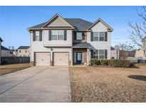 Charming two-story home featuring a two-car garage, complemented by manicured landscaping and a well-maintained front yard at 520 Harmony Way, Locust Grove, GA 30248