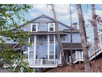 Charming two-story townhome featuring a light blue exterior and a white railed porch surrounded by trees at 3980 Riverlook Se Pkwy # 203, Marietta, GA 30067