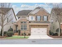 Brick two-story house with a three-car garage and manicured lawn at 7250 Jamestown Dr, Alpharetta, GA 30005