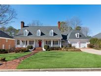 Charming home featuring a welcoming front porch, manicured lawn, and attached two-car garage at 1449 Brentford Cv, Snellville, GA 30078