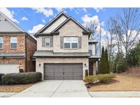 Two-story brick home with attached garage and landscaping at 8775 Village Pl, Suwanee, GA 30024