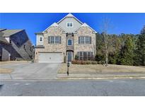 Brick two-story house with a three-car garage and landscaping at 490 La Perla Dr, Sugar Hill, GA 30518