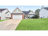 Tan brick house with white garage door and well-manicured lawn at 559 Ransom Way, Stockbridge, GA 30281