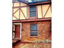Charming two-story townhouse showcasing brick facade, windows with security bars, and a cozy entrance with an opened security gate at 3278 Abbeywood Dr, Decatur, GA 30034