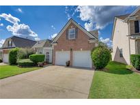 Brick home with two-car garage and landscaped yard at 1305 Leisure Lake Dr, Lawrenceville, GA 30044