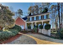 Two-story house with brick and green siding, a porch, and landscaping at 1019 Braelin Ct, Woodstock, GA 30189