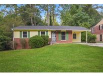 Brick ranch house with green accents, a covered carport, and a spacious lawn at 2907 Renfro Nw Dr, Atlanta, GA 30318