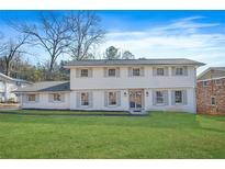 Two story house with white brick exterior, gray shutters, and a large green lawn at 3970 Somerled Trl, Atlanta, GA 30349