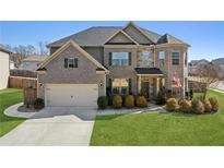 Brick two-story house with a three-car garage and landscaped lawn at 5110 Meridian Pass, Cumming, GA 30028