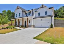 Two-story white farmhouse with gray stone accents, a large driveway, and landscaping at 399 Tillman Pass, Woodstock, GA 30188