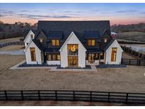 Luxury farmhouse exterior at dusk; two-story home with black roof and white siding at 5180 Howard Rd, Cumming, GA 30040