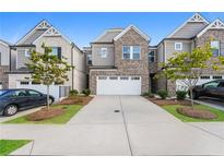 Brick front exterior of townhome with 2-car garage and landscaping at 1267 Sunny Lake Dr, Lawrenceville, GA 30043