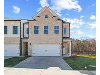 Charming, new construction two-story townhouse with a two car garage and tan brick facade at 891 Eagle Ave, Riverdale, GA 30296
