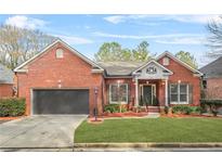 Brick ranch home with attached garage, manicured lawn, and landscaping at 127 Ennisbrook Se Dr, Smyrna, GA 30082