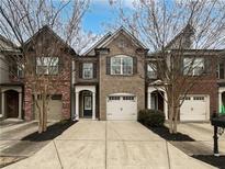 Brick front exterior of townhome with 2-car garage and landscaping at 1710 Garbrooke Cv, Lawrenceville, GA 30046