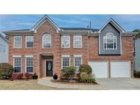 Brick two-story house with a three-car garage and landscaping at 5102 Anclote Dr, Alpharetta, GA 30022