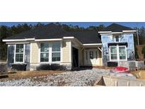 New construction home featuring a dark roof, light yellow siding, and white trim around the windows and entrance at 15 Cambridge Ln, Dallas, GA 30157