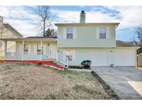 Two-story light green house with a two-car garage and a front porch at 6137 Raleigh Oaks Ct, Lithonia, GA 30058