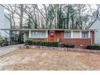 Brick ranch home with red door, landscaping, and a driveway at 2848 Baker Ridge Nw Dr, Atlanta, GA 30318