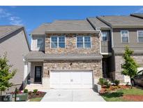 Two-story townhome with stone facade, two-car garage, and landscaped front yard at 1720 Habersham Villa Dr, Cumming, GA 30041