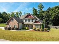 Brick two-story house with a landscaped lawn and mature trees at 307 Cinnamon Bark Pass, Locust Grove, GA 30248