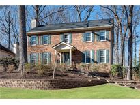 Brick two-story house with green shutters, landscaping, and stone retaining wall at 4187 Westchester Ne Trce, Roswell, GA 30075