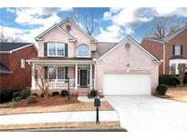 Two-story brick home with a front porch, attached garage, and landscaping at 2024 Gramercy Cir, Atlanta, GA 30341