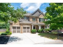 Two-story brick home with a large front yard, two-car garage, and a covered porch at 5540 Fords Crossing Nw Ct, Acworth, GA 30101