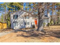 Charming two-story home with vinyl siding and a bright orange front door surrounded by mature trees at 4547 Doral Sw Dr, Atlanta, GA 30331