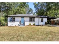 Newly renovated Ranch home with light brick exterior, spacious lawn and light blue front door at 1709 Valencia Rd, Decatur, GA 30032