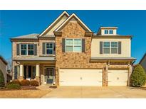 Two-story house with stone and brick accents, two-car garage, and landscaping at 5390 Chestnut Dr, Cumming, GA 30040