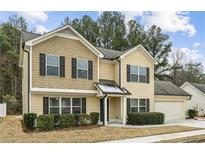 Two-story house with beige vinyl siding, dark brown shutters, and a two-car garage at 320 Eagles Pkwy, Covington, GA 30014