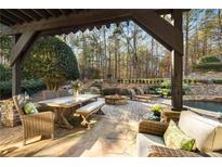 Spacious backyard patio with fire pit, seating area, and stone retaining wall at 6229 Grand Loop Rd, Sugar Hill, GA 30518