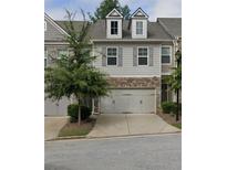 Two-story townhome with gray siding, stone accents, and a two-car garage at 1563 Butternut Cv, Stone Mountain, GA 30083