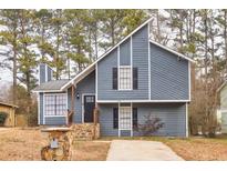 Gray house with stone accents and a paved driveway, nestled among trees at 6300 Creekford Dr, Lithonia, GA 30058