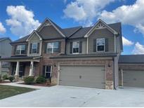 Two-story house with gray siding, three-car garage, and landscaping at 1890 Cobblefield Cir, Dacula, GA 30019