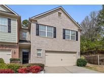 Charming brick townhome featuring black shutters, attached garage, and well-maintained landscaping at 2166 Waterford Park Dr, Lawrenceville, GA 30044