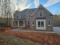 Two-story brick home featuring a covered porch, gray shutters, and a driveway, surrounded by a wooded area at 7449 Waterview Cv, Douglasville, GA 30135