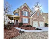 Charming two-story brick home featuring a covered front porch and a two-car garage at 5575 Twelve Oaks Dr, Cumming, GA 30028