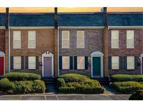 Brick townhomes featuring colorful doors, black shutters, and manicured landscaping at 245 Winding River Dr # E, Atlanta, GA 30350