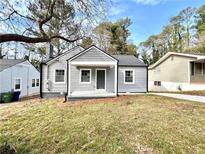 Charming gray home featuring a cozy front porch and a well-maintained lawn, surrounded by mature trees at 1271 Lorenzo Sw Dr, Atlanta, GA 30310