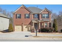 Charming two-story brick home with well-manicured lawn, two-car garage, and inviting curb appeal at 1565 Horseshoe Creek Ln, Cumming, GA 30041