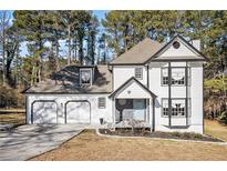 Two-story white house with black accents, two-car garage, and landscaping at 6492 Swift Creek Rd, Lithonia, GA 30058