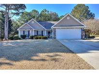 Beige house with a white garage door and landscaping at 340 Annslee Cir, Loganville, GA 30052