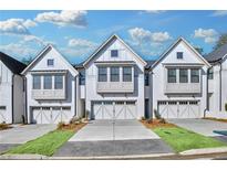 Three-story townhouses with white brick exteriors and two-car garages at 134 Briargate Dr # 16, Johns Creek, GA 30097