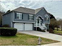 Charming two-story home features a two-car garage and a welcoming front porch with white railings at 1379 Paddocks Way, Powder Springs, GA 30127