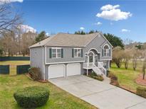 Charming two-story home featuring a two-car garage, landscaped front yard, and inviting front porch with white railing at 1379 Paddocks Way, Powder Springs, GA 30127