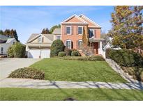 Brick and shingle two-story house with a two-car garage and landscaped lawn at 4974 Dovecote Trl, Suwanee, GA 30024