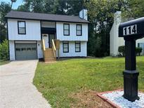 Two-story house with white siding, gray garage door, and a wooden deck at 114 Jousters Ln, Lawrenceville, GA 30044