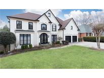 Stunning two-story house with a white exterior, black accents, and a beautifully landscaped lawn at 3000 Leeds Garden Ln, Alpharetta, GA 30022